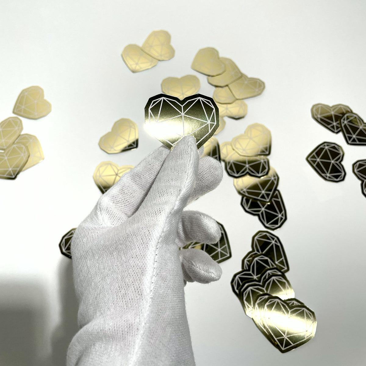 Gold mirror die-cut sticker catching the light in a gloved hand