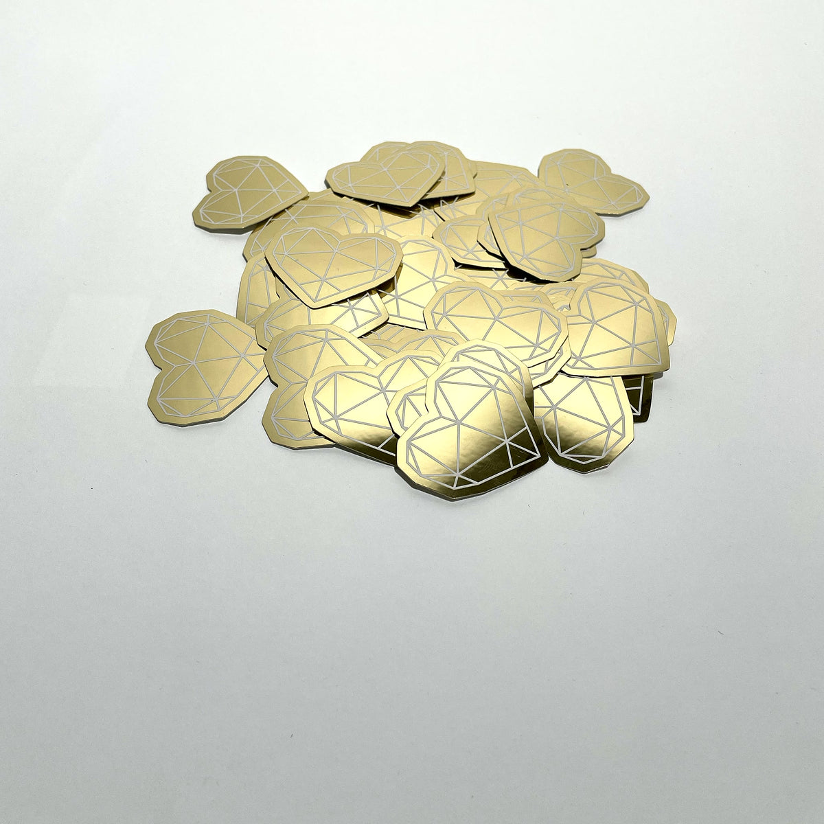 Pile of gold mirror die-cut stickers on a white surface