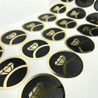 Round labels with gold print on a black background