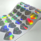 Holographic die-cut hearts shifting colour with the viewing angle