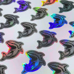 Holographic die-cut sharks changing colour as the sheet moves