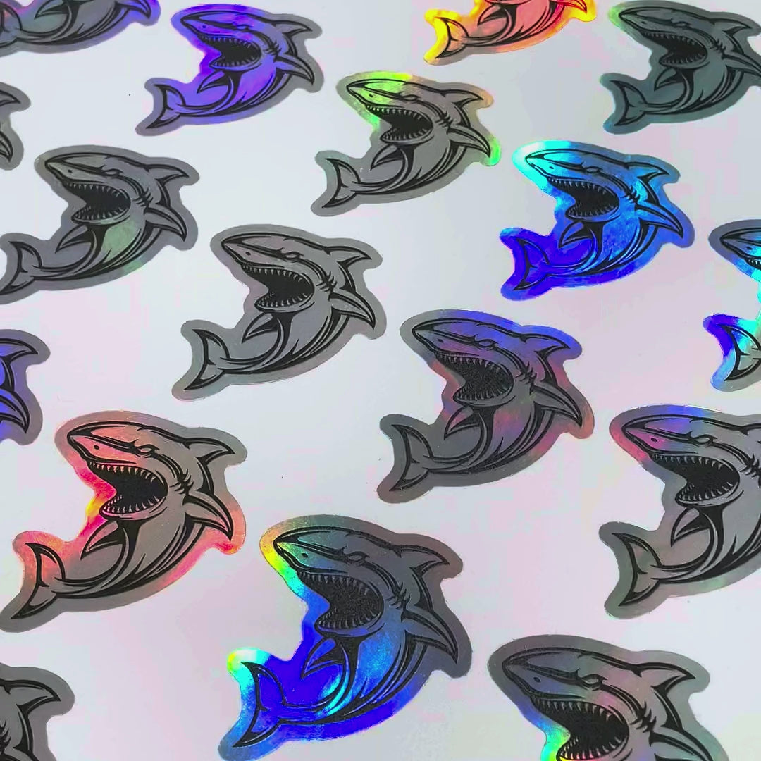 Holographic die-cut sharks changing colour as the sheet moves