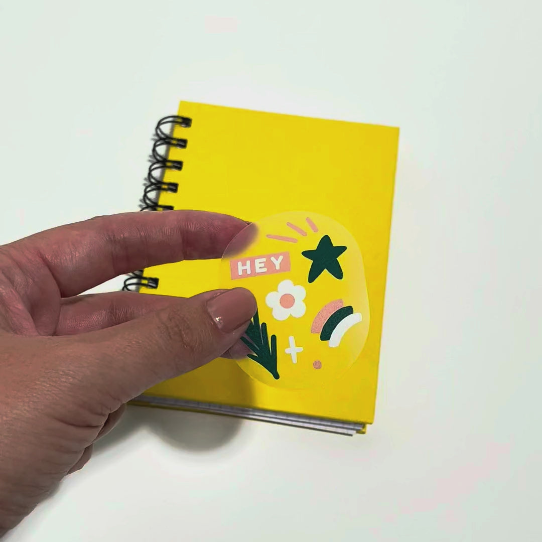 Applying a clear round label with white underprint to a notebook