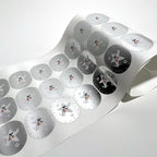 Metallic silver round labels curling off the roll
