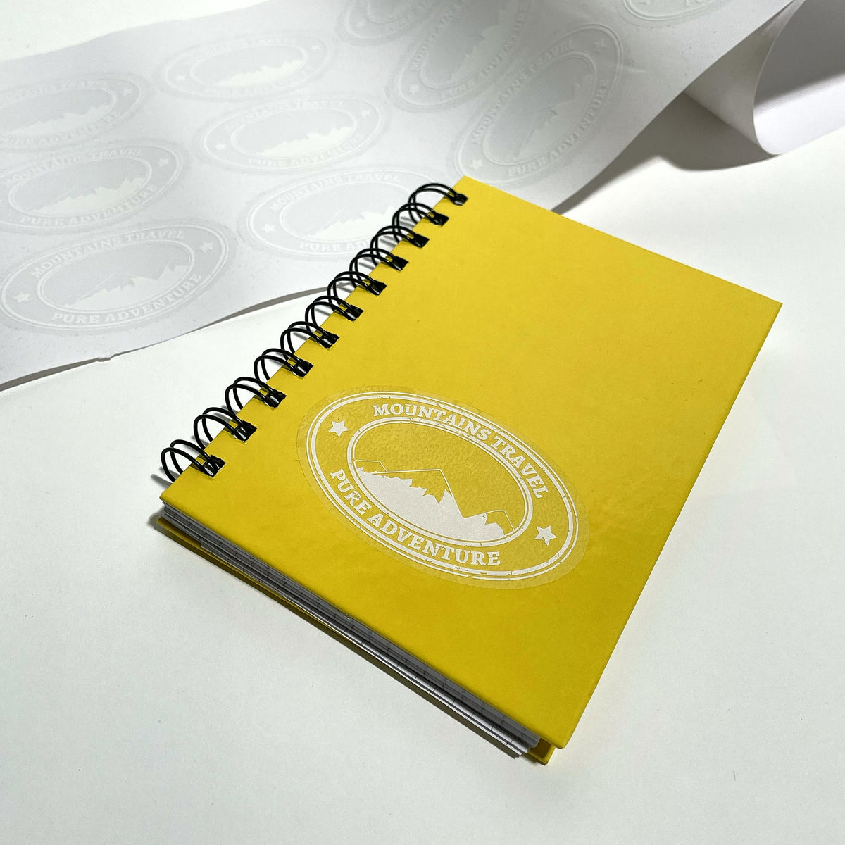 Clear round label with white underprint applied to a yellow notebook